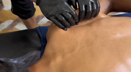 Therapist at MAMU MASSAGE in Shah Alam, Selangor, MY performing back massage with black gloves.
