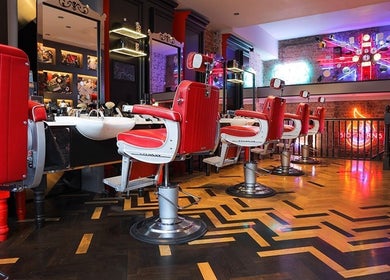 Red barber chairs at Ted's Grooming Room: Chelsea - King's Road, London, England, GB with vibrant decor.