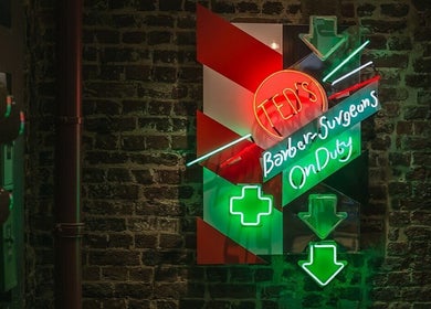 Neon sign at Mortimer Street - Regents, Ted's Grooming Room in London, England, GB on a brick wall.