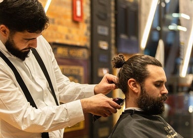 Professional barber at Strand - The Strand, Ted's Grooming Room in London, England, GB styling a client's hair.