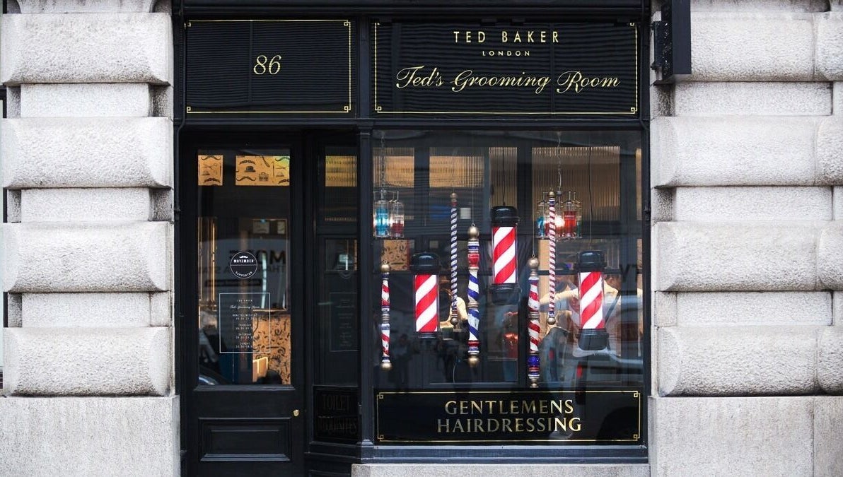 Elegant exterior of Moorgate, Ted's Grooming Room in London, England, GB showcasing barber poles and branding.