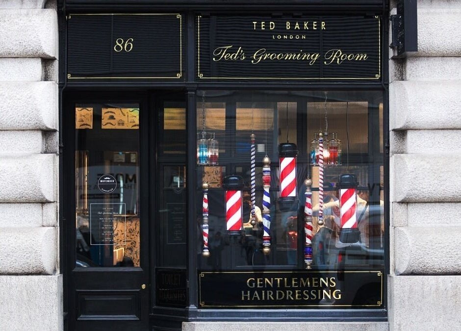 Elegant exterior of Moorgate, Ted's Grooming Room in London, England, GB showcasing barber poles and branding.
