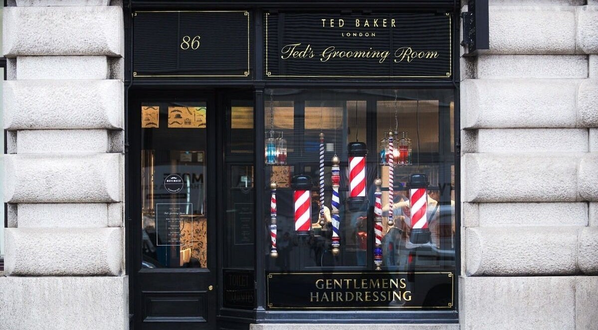 Elegant exterior of Moorgate, Ted's Grooming Room in London, England, GB showcasing barber poles and branding.
