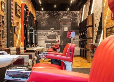 Stylish interior of Strand - The Strand, Ted's Grooming Room in London, England, GB with red barber chairs.