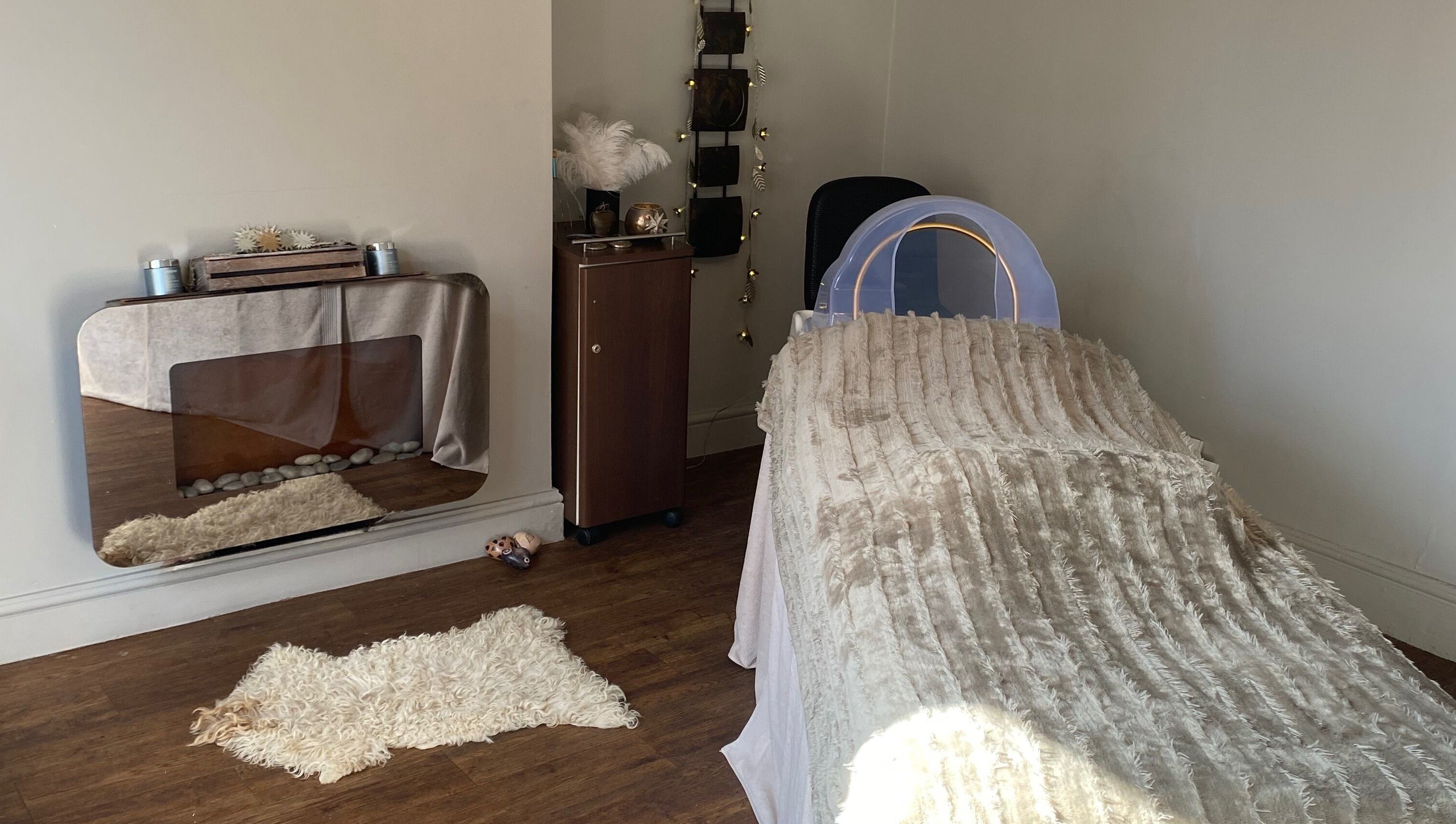 A serene treatment room at The Skin Refinery, Birmingham, England, GB, with a cushioned bed and elegant decor.