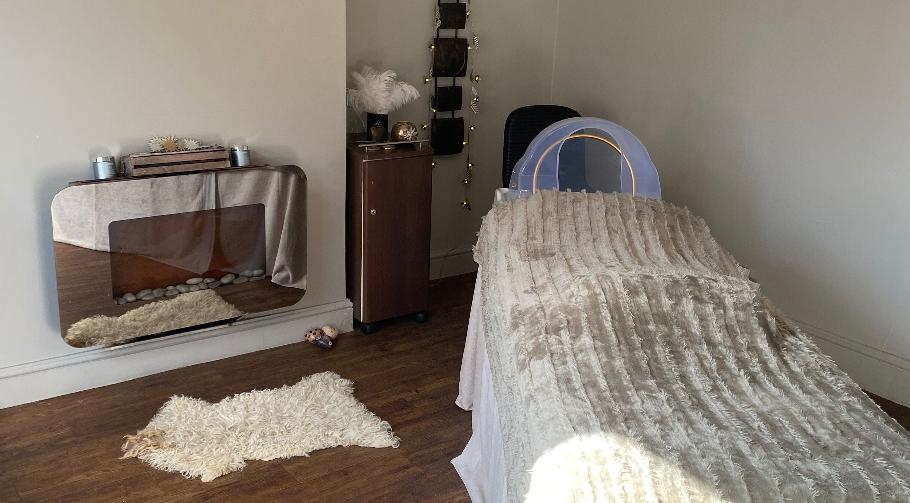 A serene treatment room at The Skin Refinery, Birmingham, England, GB, with a cushioned bed and elegant decor.