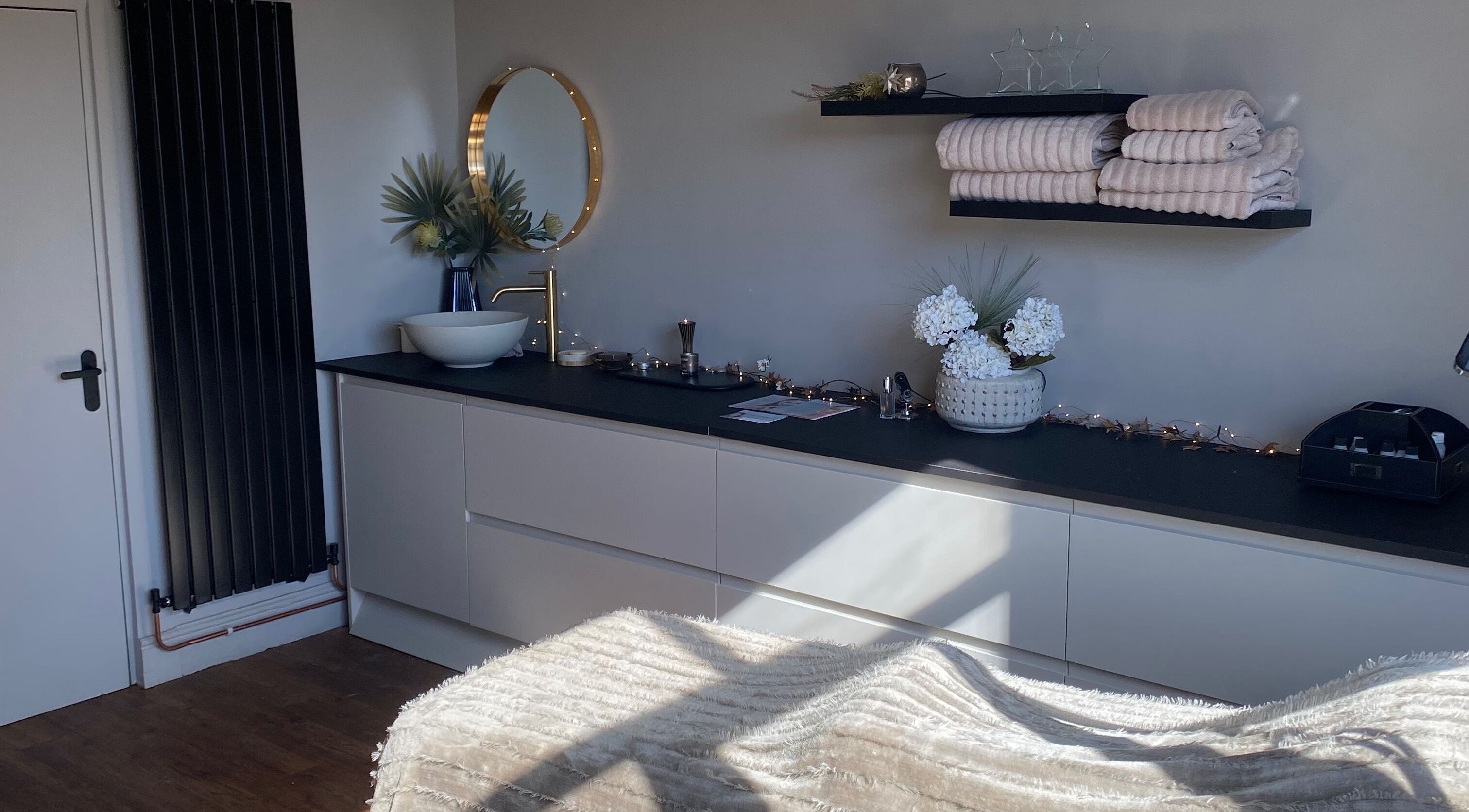 Modern treatment room at The Skin Refinery, Birmingham, England, featuring plush towels and chic decor.