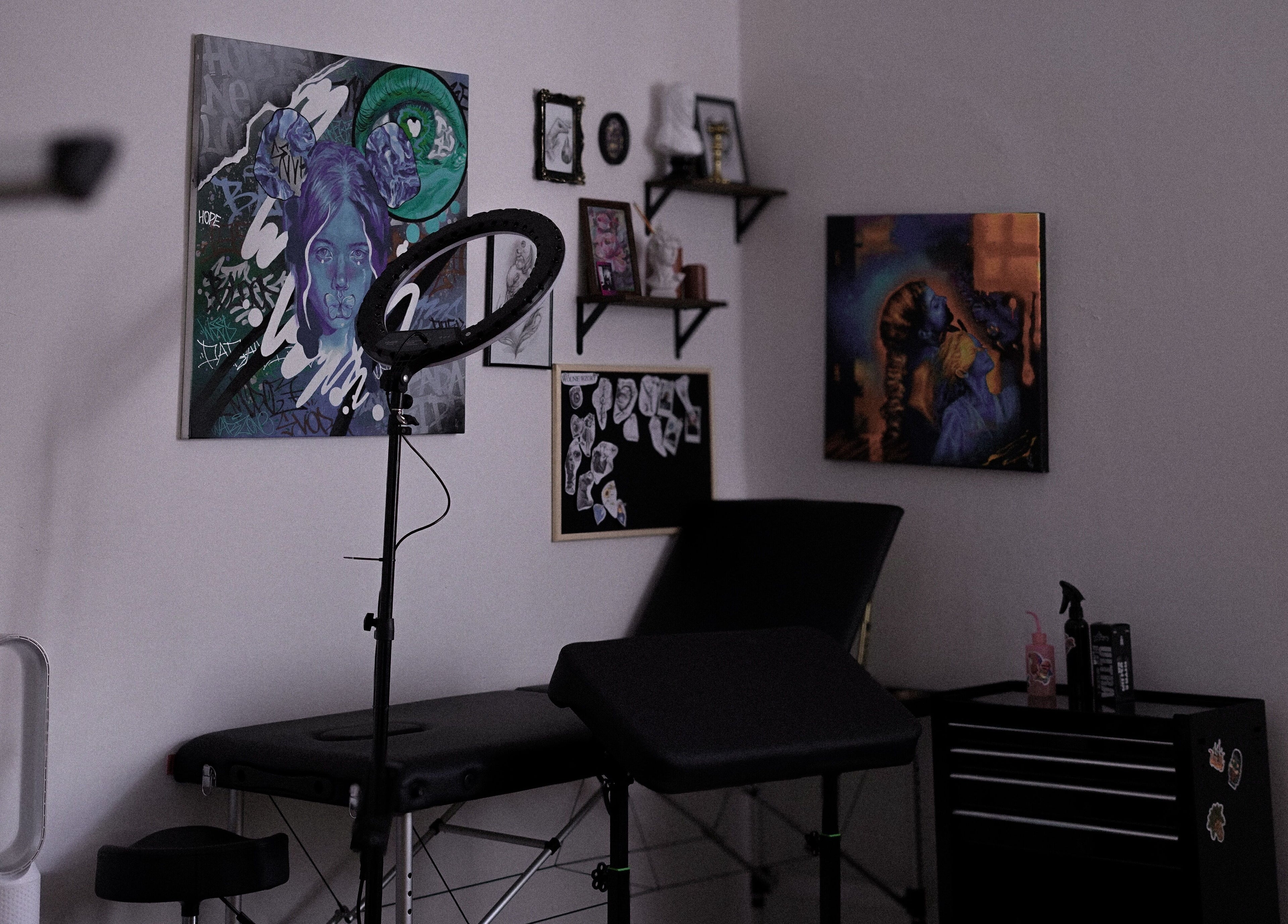 Wnętrze Somah Tattoo & Piercing w Warszawa, Województwo Mazowieckie. Sztuka na ścianach, stolik i lampa.