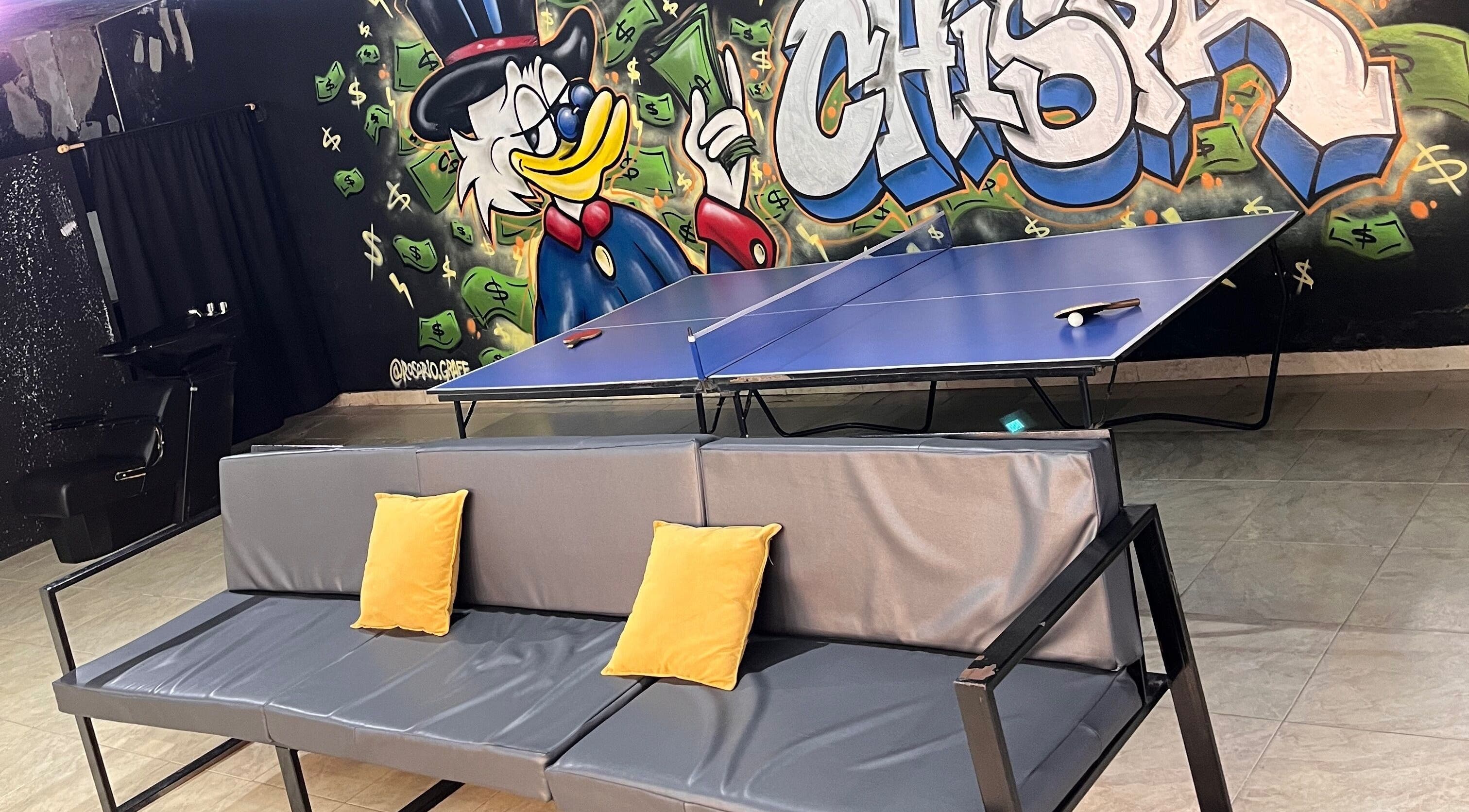 Colorful mural, couch, and ping pong table at Barbería La Chispa, Rosario, Santa Fe, AR inviting creative energy.