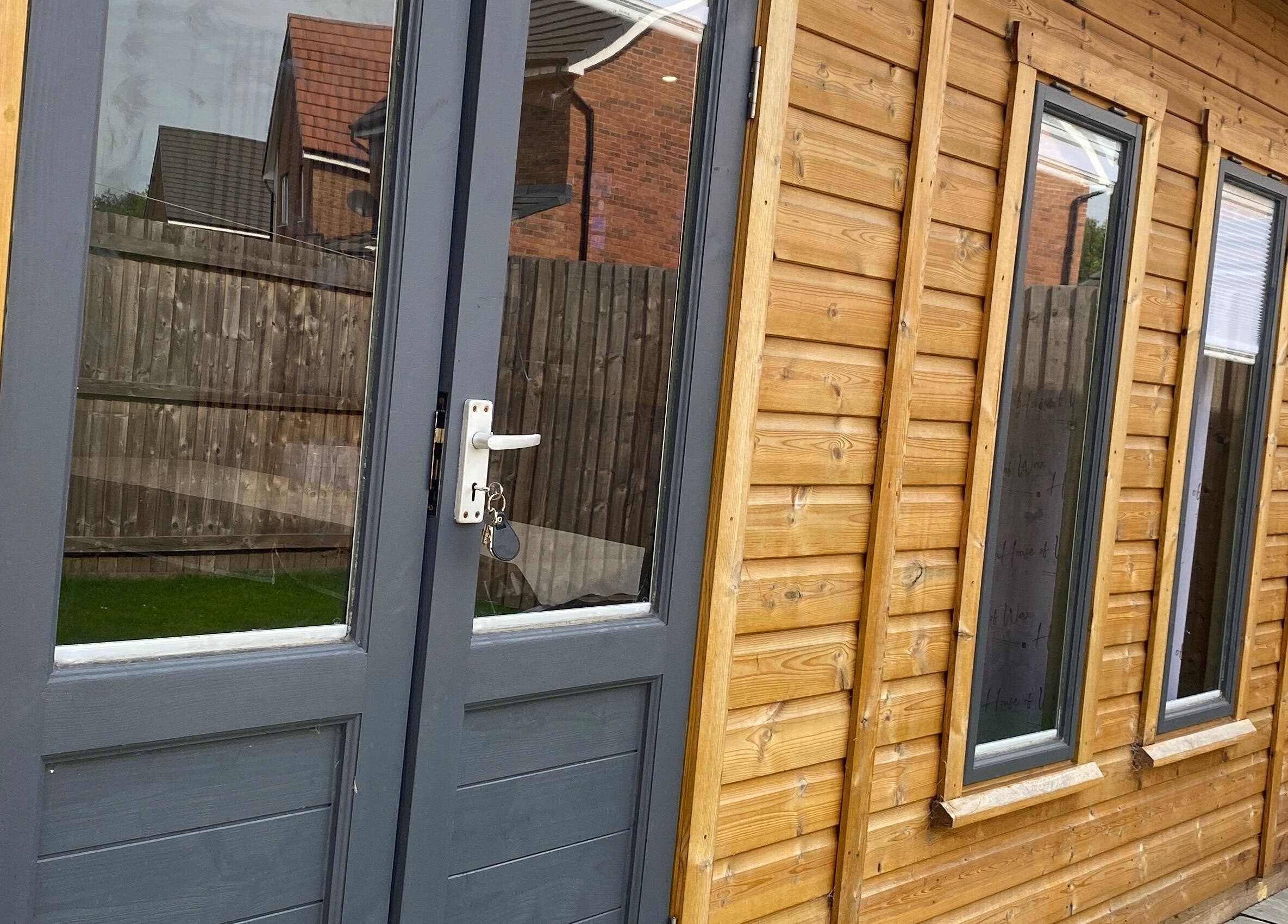 Wooden exterior of House of Wax | Waxing Salon in St Helens, England, GB with modern glass doors.