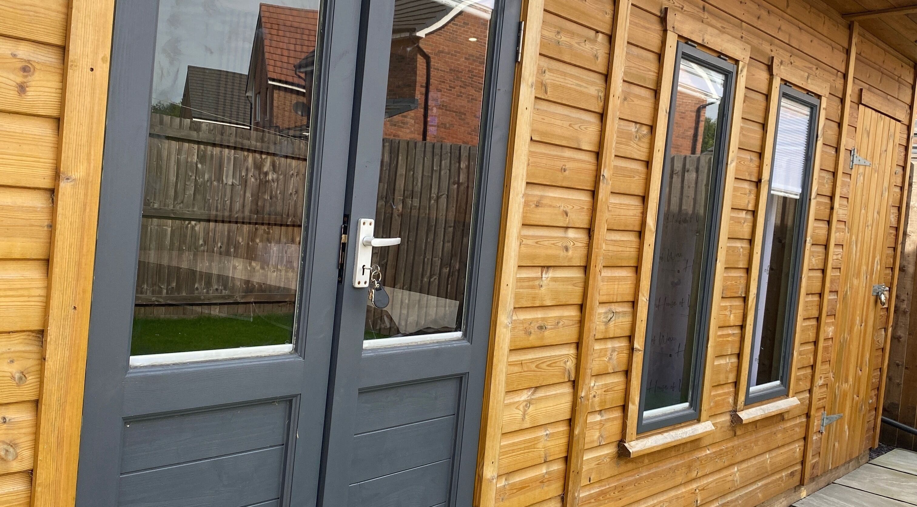 Wooden exterior of House of Wax | Waxing Salon in St Helens, England, GB with modern glass doors.