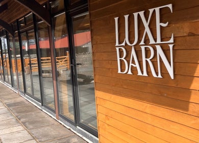 Elegant wood facade of Luxe Barn at AlexandraJaine Extensions in Tickenham, England, GB with large glass windows.