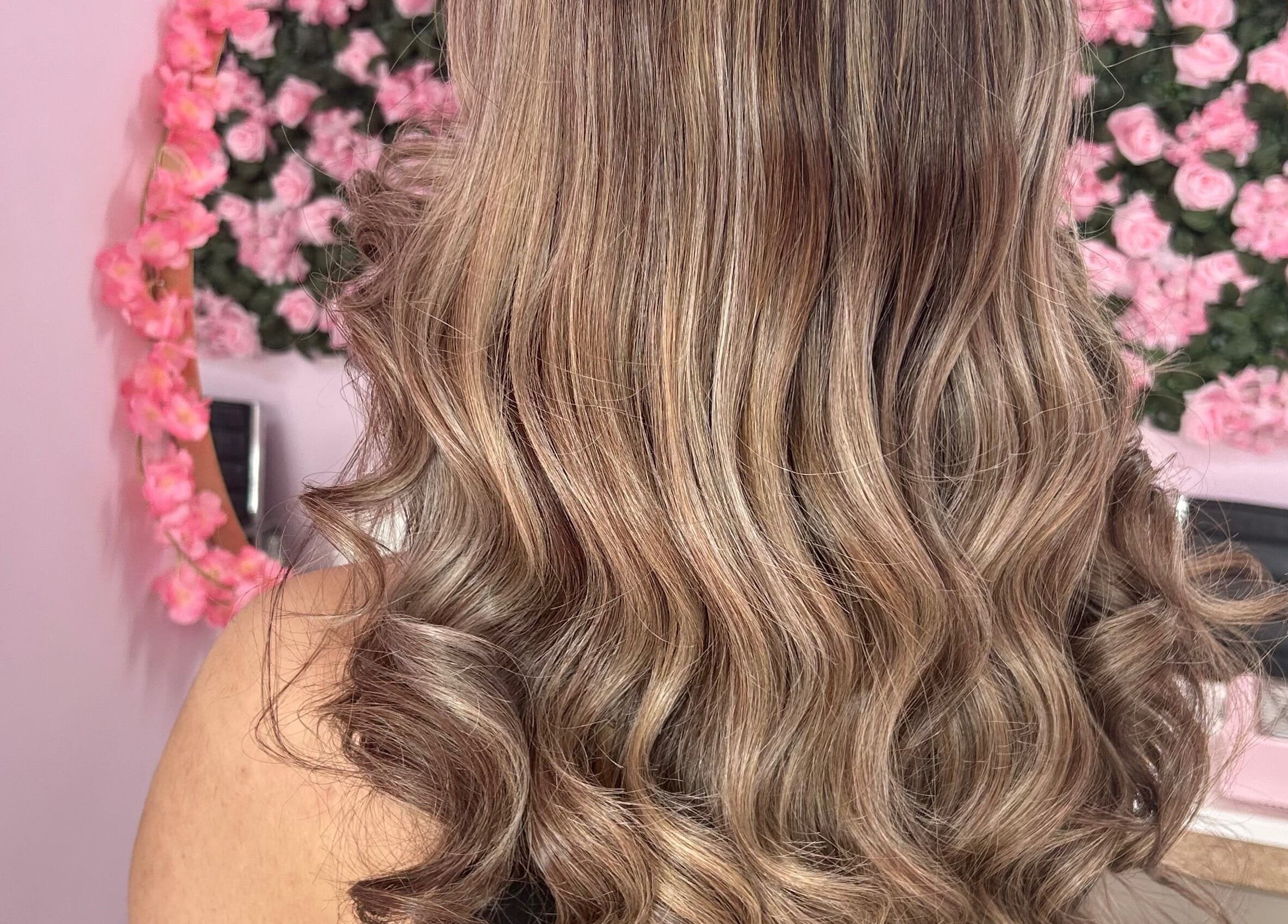Elegant wavy hairstyle created at Nuabeauty, Bradford, England, GB with a pink floral background.