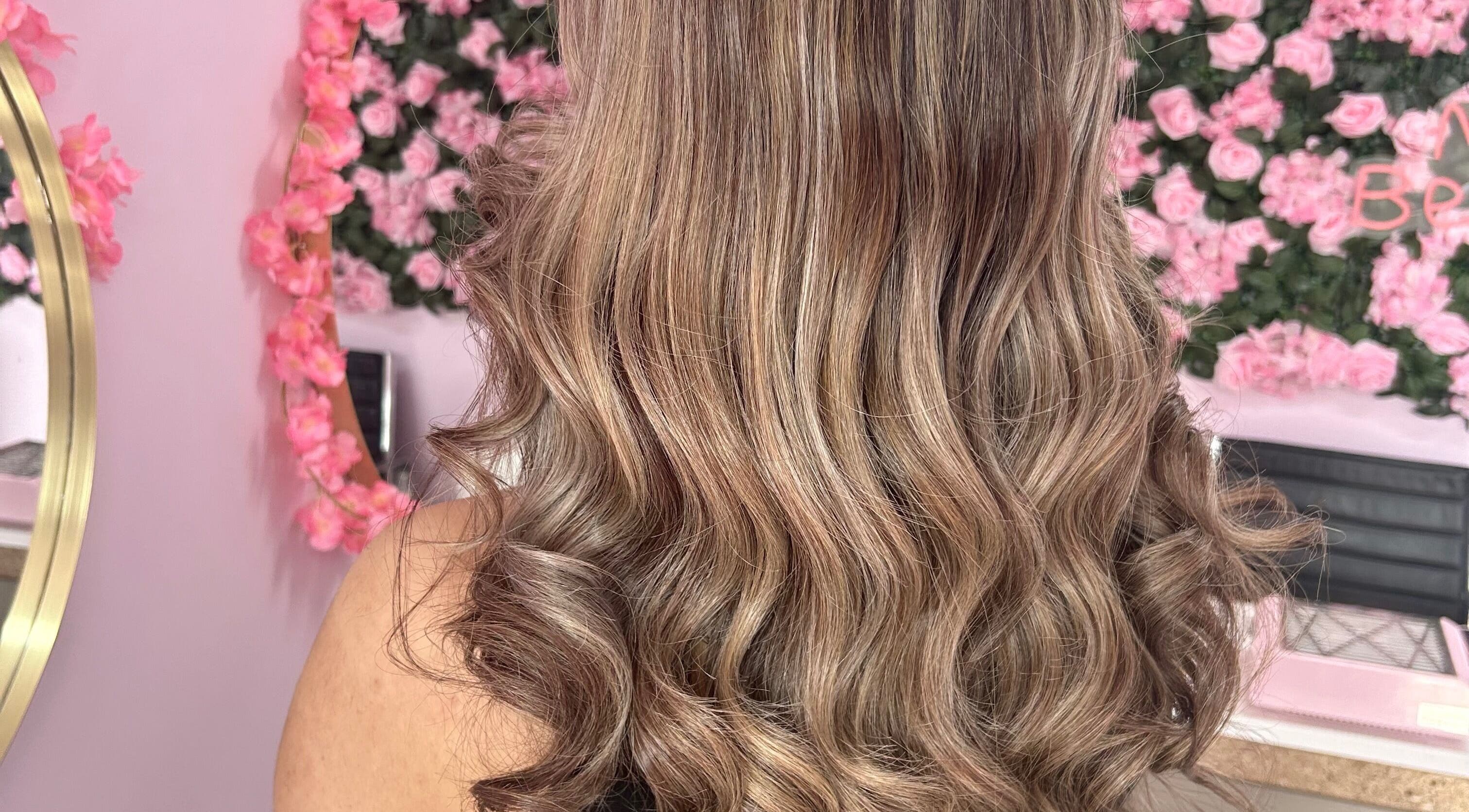 Elegant wavy hairstyle created at Nuabeauty, Bradford, England, GB with a pink floral background.