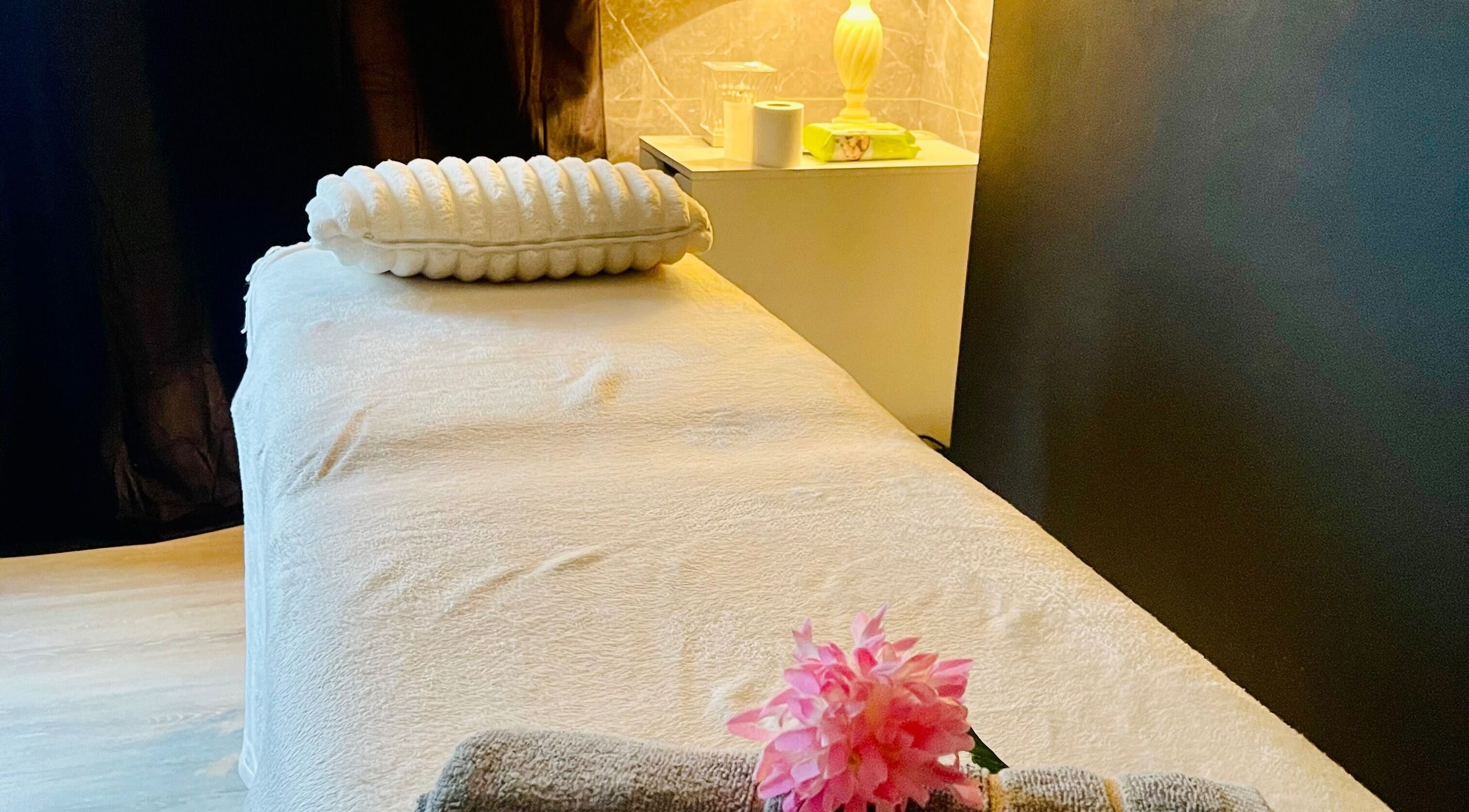 Massage table at Tuina Massage Spa, Belfast, Northern Ireland, GB with soft lighting and floral accents.