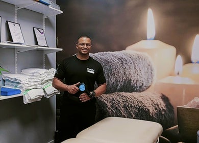 Massage therapist at VVV, Nottingham, GB, with calming candles and towels in a serene treatment room.