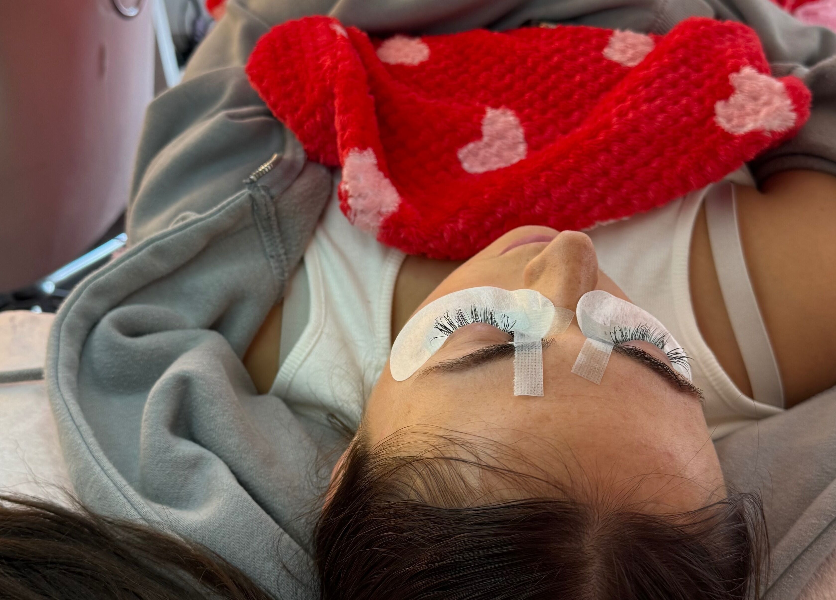 Client enjoying eyelash extensions at Phoebeloulashes, Cardiff, Wales, GB with cozy blanket and eye pads.