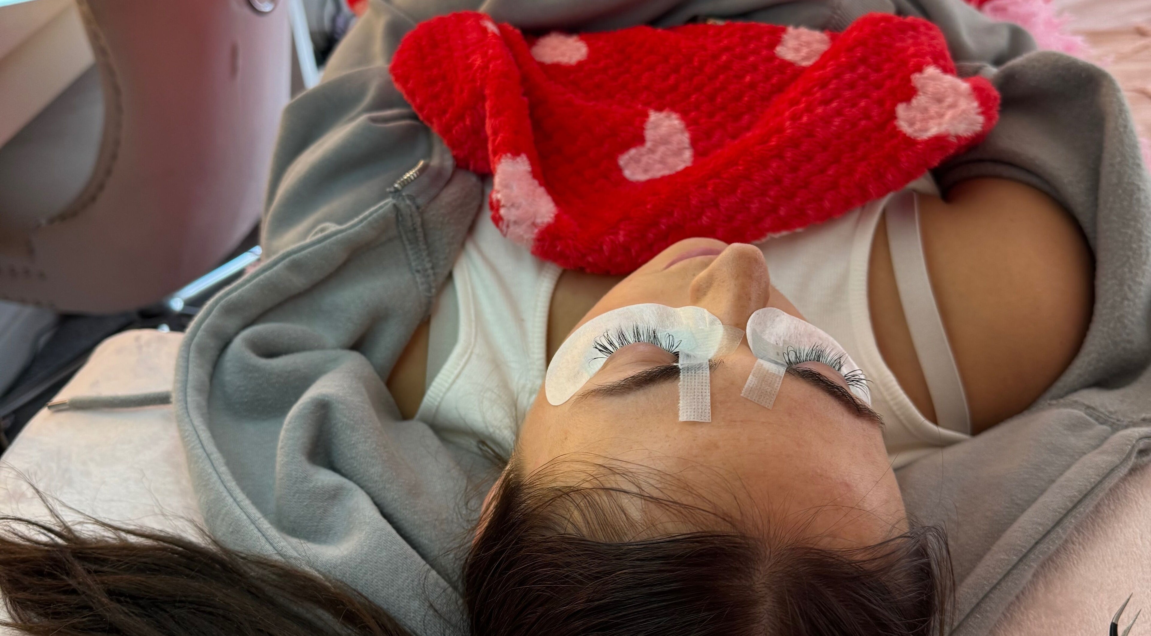 Client enjoying eyelash extensions at Phoebeloulashes, Cardiff, Wales, GB with cozy blanket and eye pads.