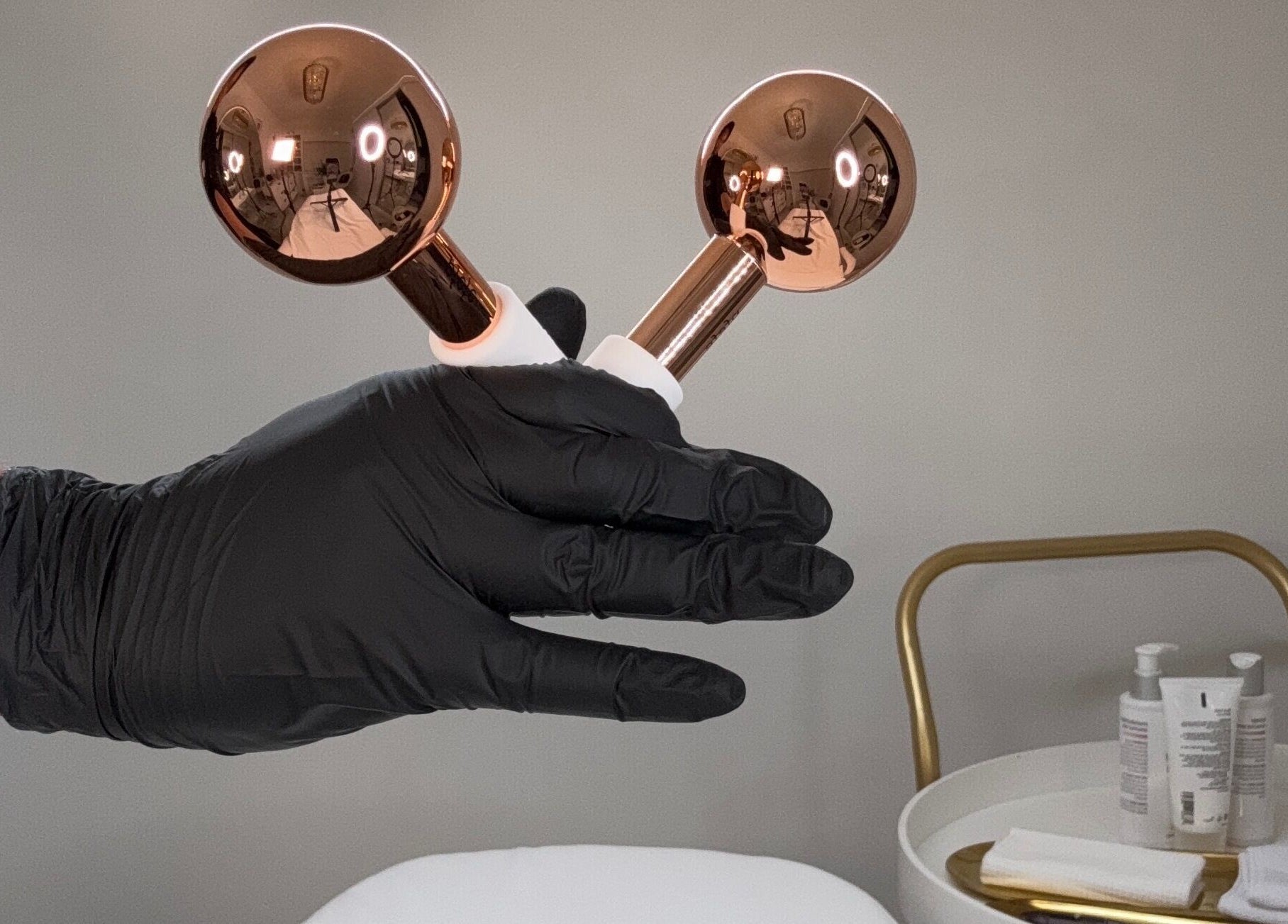 Gloved hand holds gold beauty tools at The Angel Aesthetics, Birmingham, England, GB.