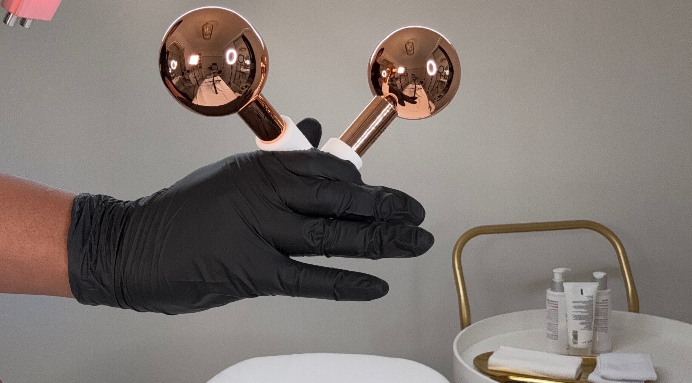 Gloved hand holds gold beauty tools at The Angel Aesthetics, Birmingham, England, GB.