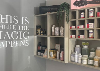 Product shelves at Hairlistic Hair Salon And Barbers, Kesgrave, England, GB with 'This is where the magic happens' sign.
