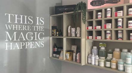 Product shelves at Hairlistic Hair Salon And Barbers, Kesgrave, England, GB with 'This is where the magic happens' sign.