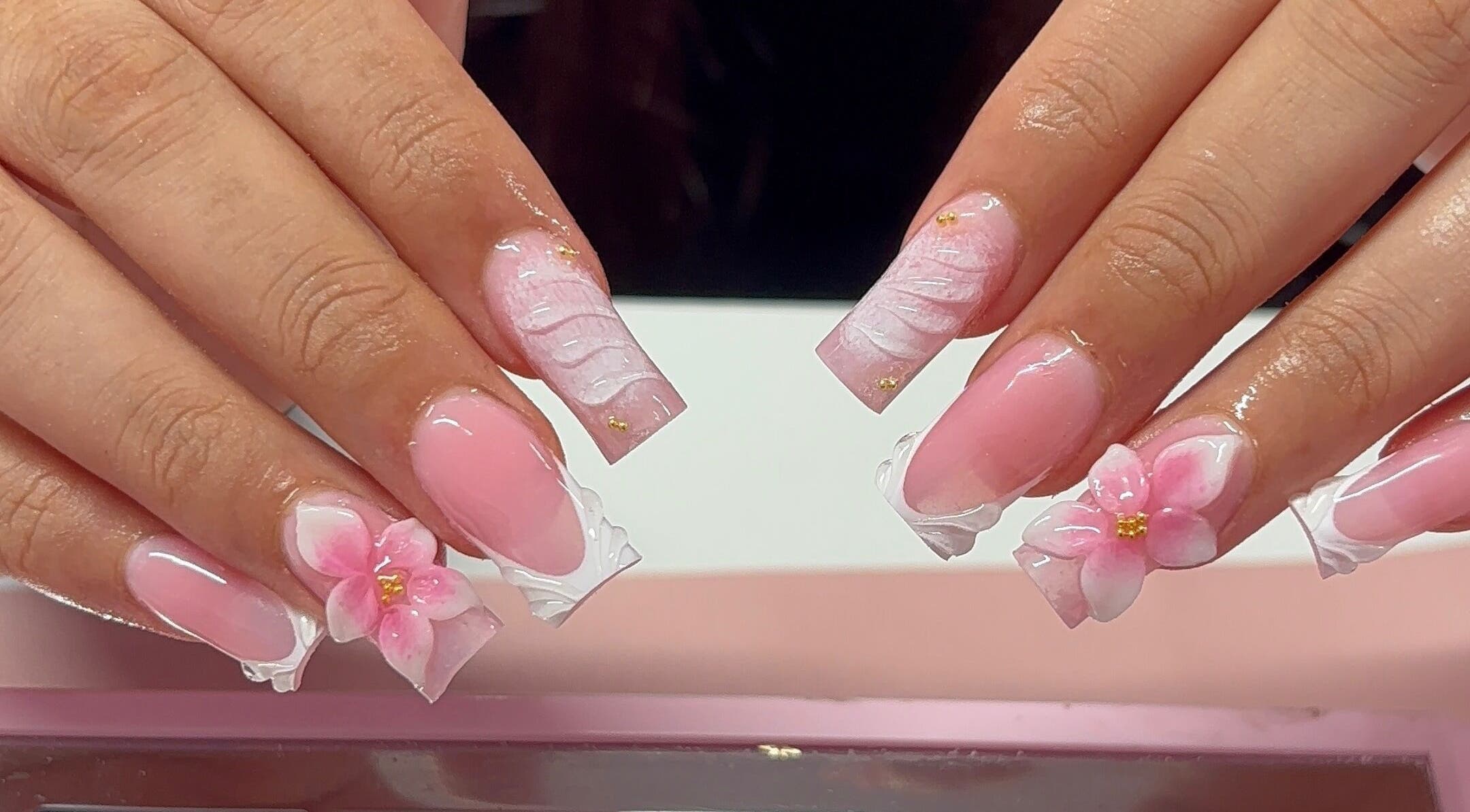 Floral acrylic nails at Nua Nails, Bradford, England, GB showcasing pink designs with delicate flowers.