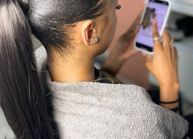 Woman with sleek ponytail using a phone at The Belle Boutique, Randburg, Gauteng, ZA.