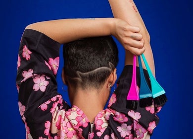 Back view of a person in floral robe holding hair tint brushes at Arise Beauty by Catalina Popa, Huddersfield, England, GB.