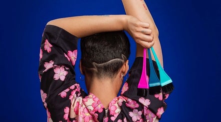 Back view of a person in floral robe holding hair tint brushes at Arise Beauty by Catalina Popa, Huddersfield, England, GB.