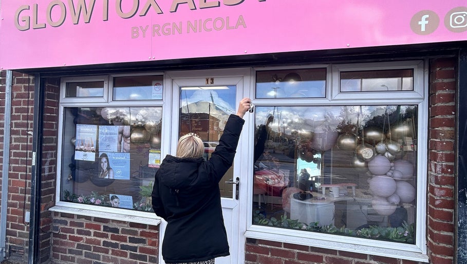Front view of The Gloss By Milly, beauty salon in Fleetwood, England, GB, featuring a pink sign and floral decor.