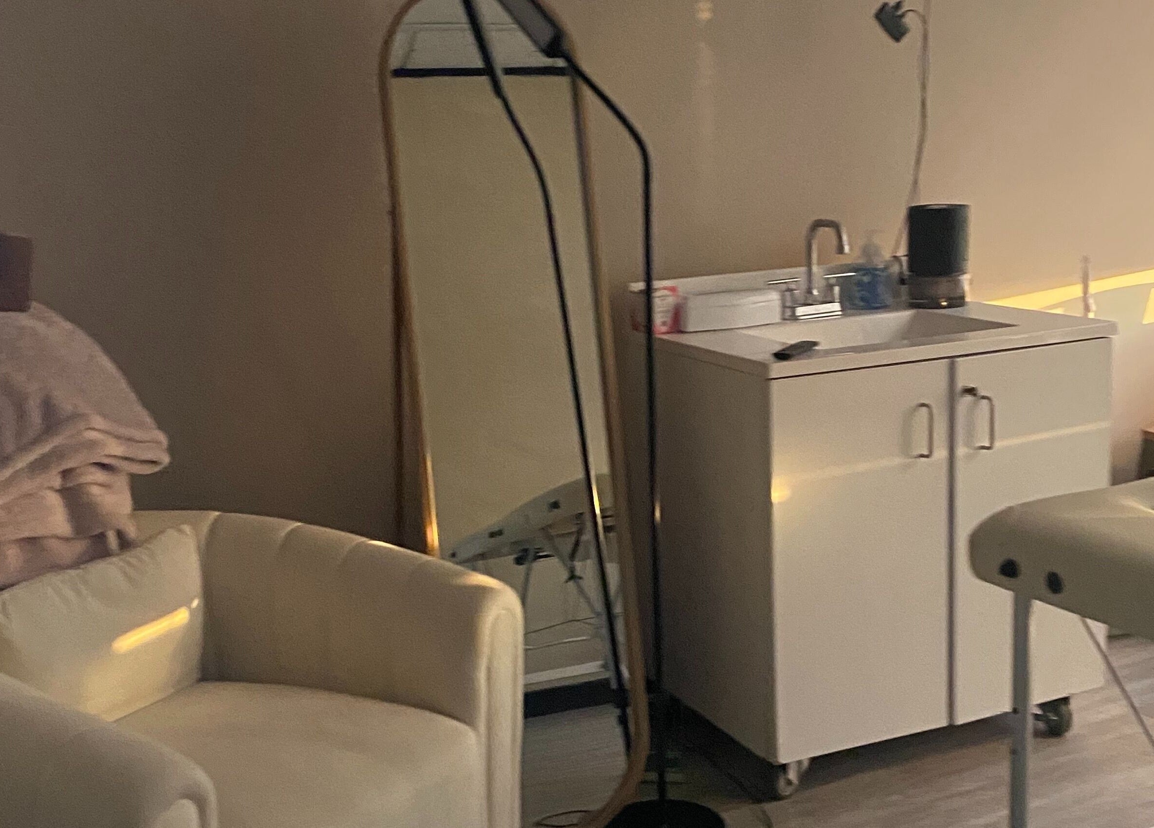 Calming spa room at Hidden Gem in Rockdale, Texas, US featuring comfortable chair and sleek mirror.