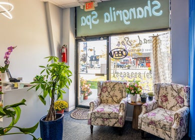 Welcoming lounge area at Shangrila Head Spa in Yorktown Heights, NY, US with floral chairs and vibrant plants.