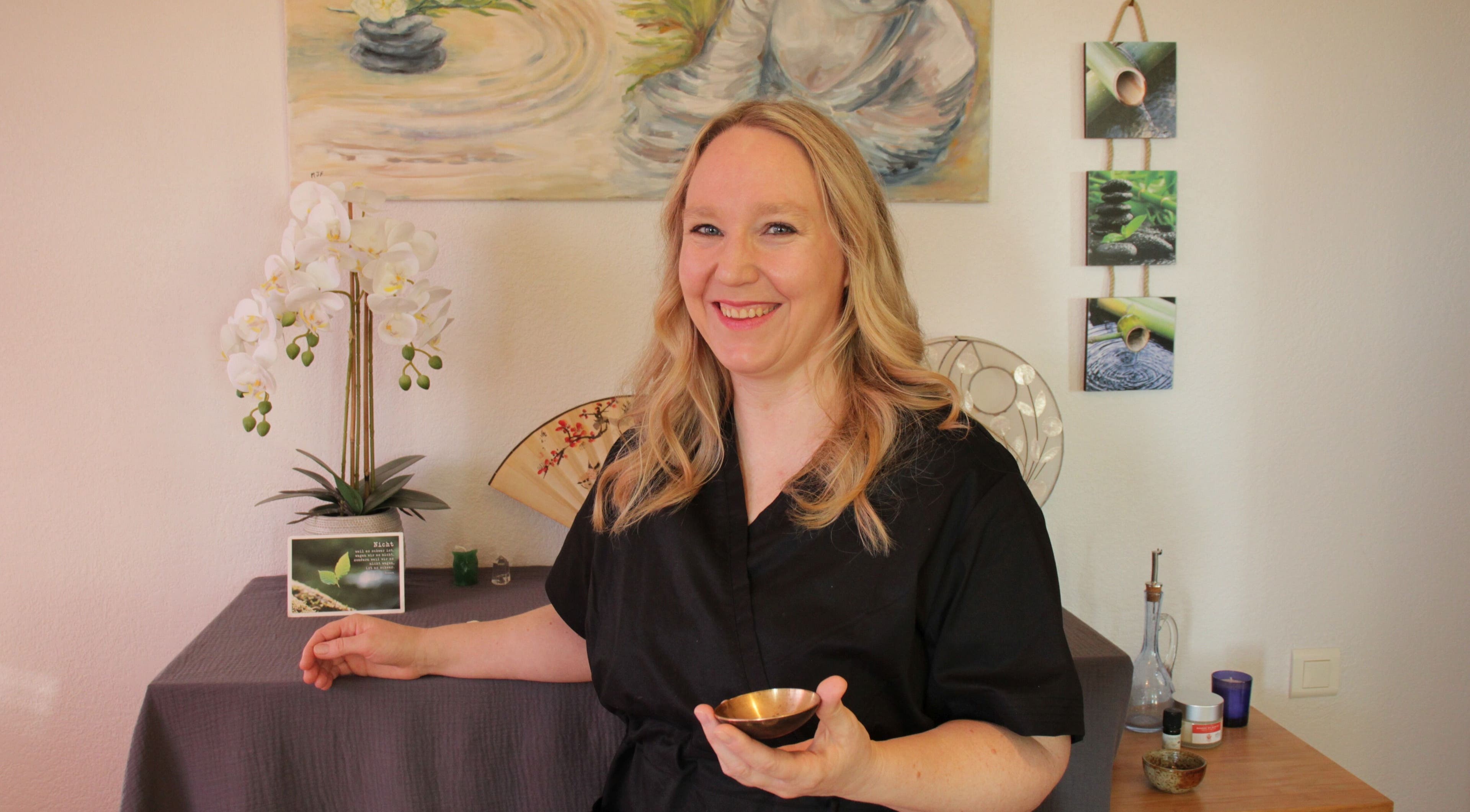 Praticienne souriante chez EnVie Massages, Pignan, Okzitanien, FR, dans un cadre relaxant avec orchidées.