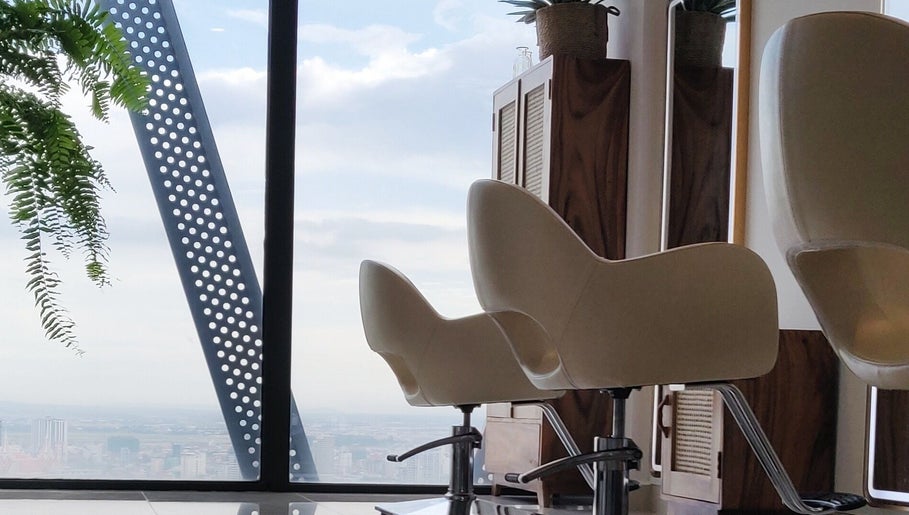Modern salon chairs at Sam Studio, overlooking Phnom Penh, Phnom Penh, KH skyline through large windows.