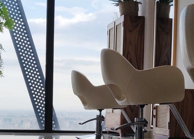 Modern salon chairs at Sam Studio, overlooking Phnom Penh, Phnom Penh, KH skyline through large windows.