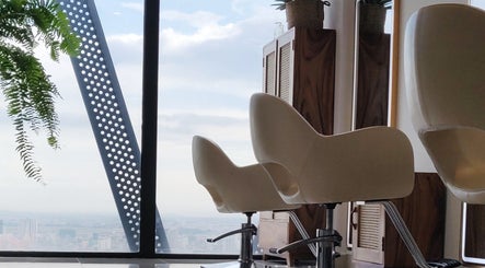 Modern salon chairs at Sam Studio, overlooking Phnom Penh, Phnom Penh, KH skyline through large windows.