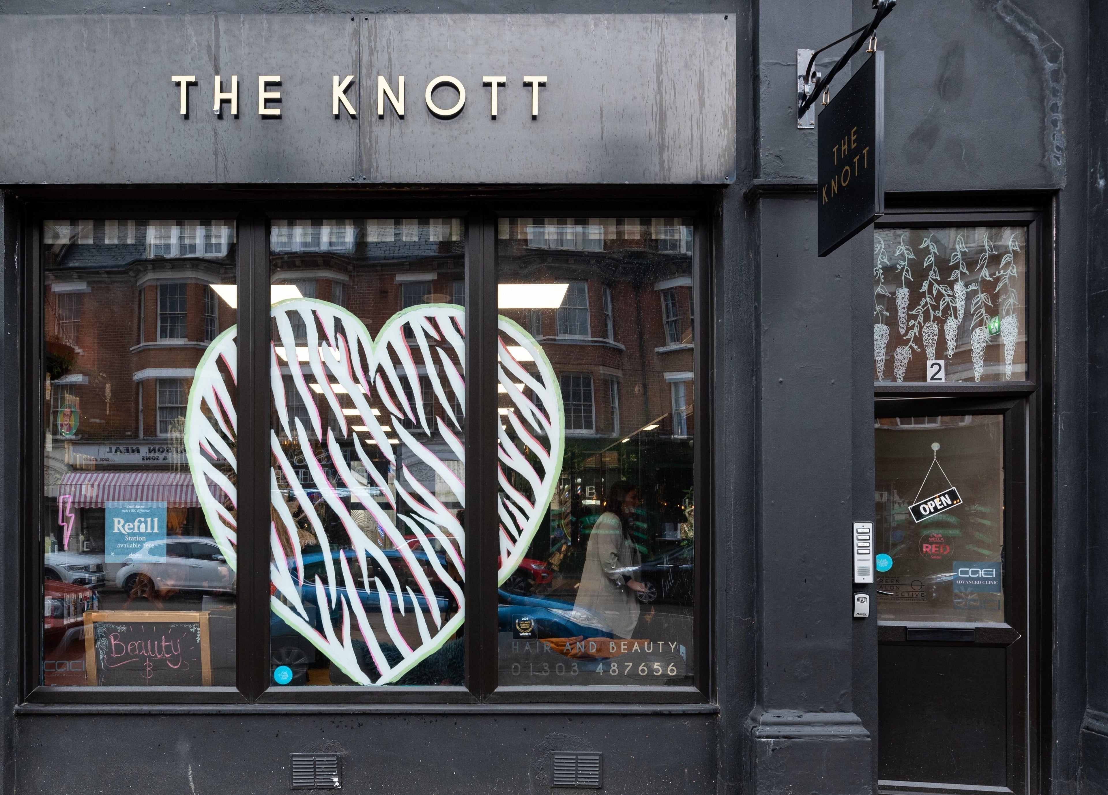 Front of 'The Knott' beauty venue in Folkestone, England, GB with stylish black exterior and large heart decoration.