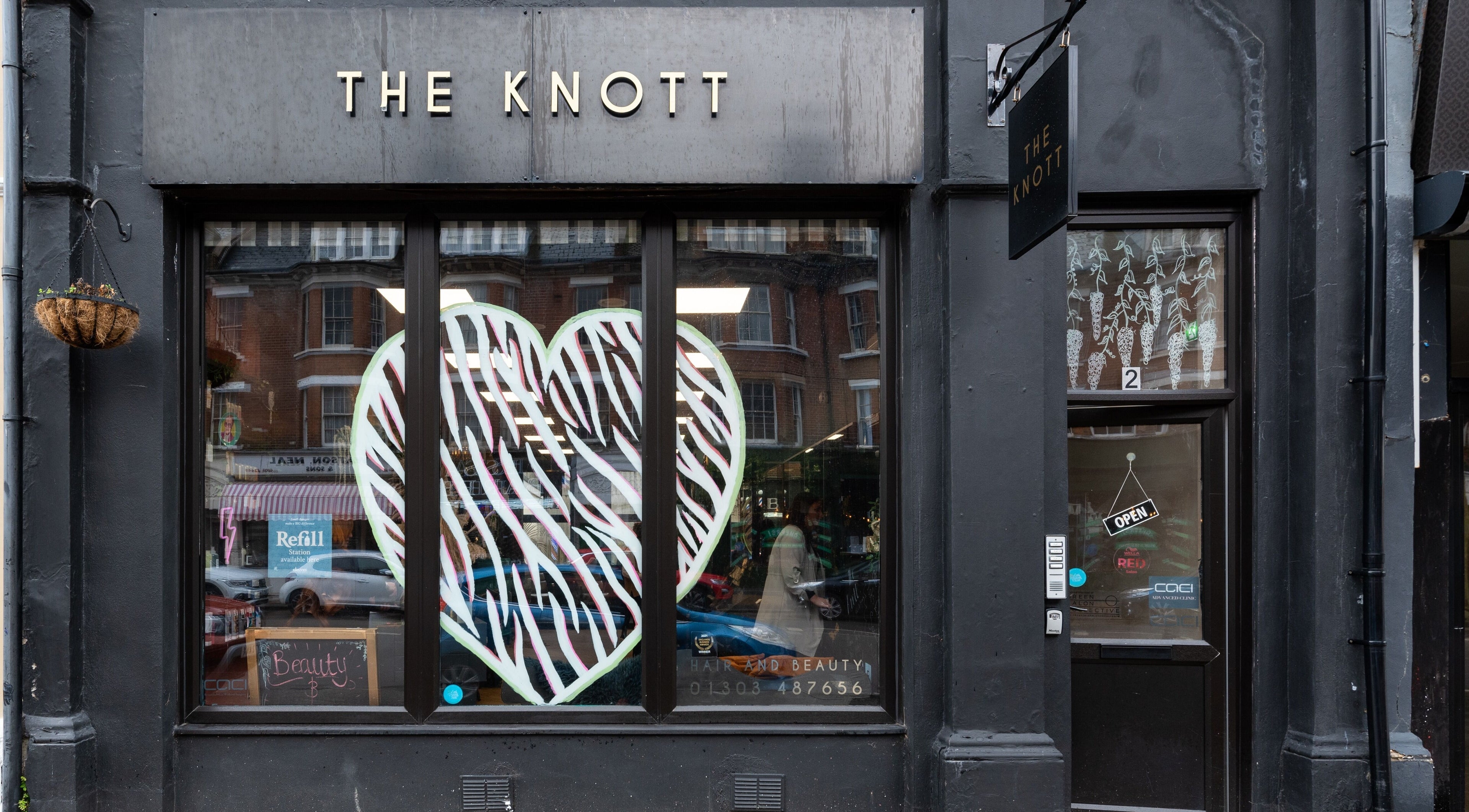 Front of 'The Knott' beauty venue in Folkestone, England, GB with stylish black exterior and large heart decoration.
