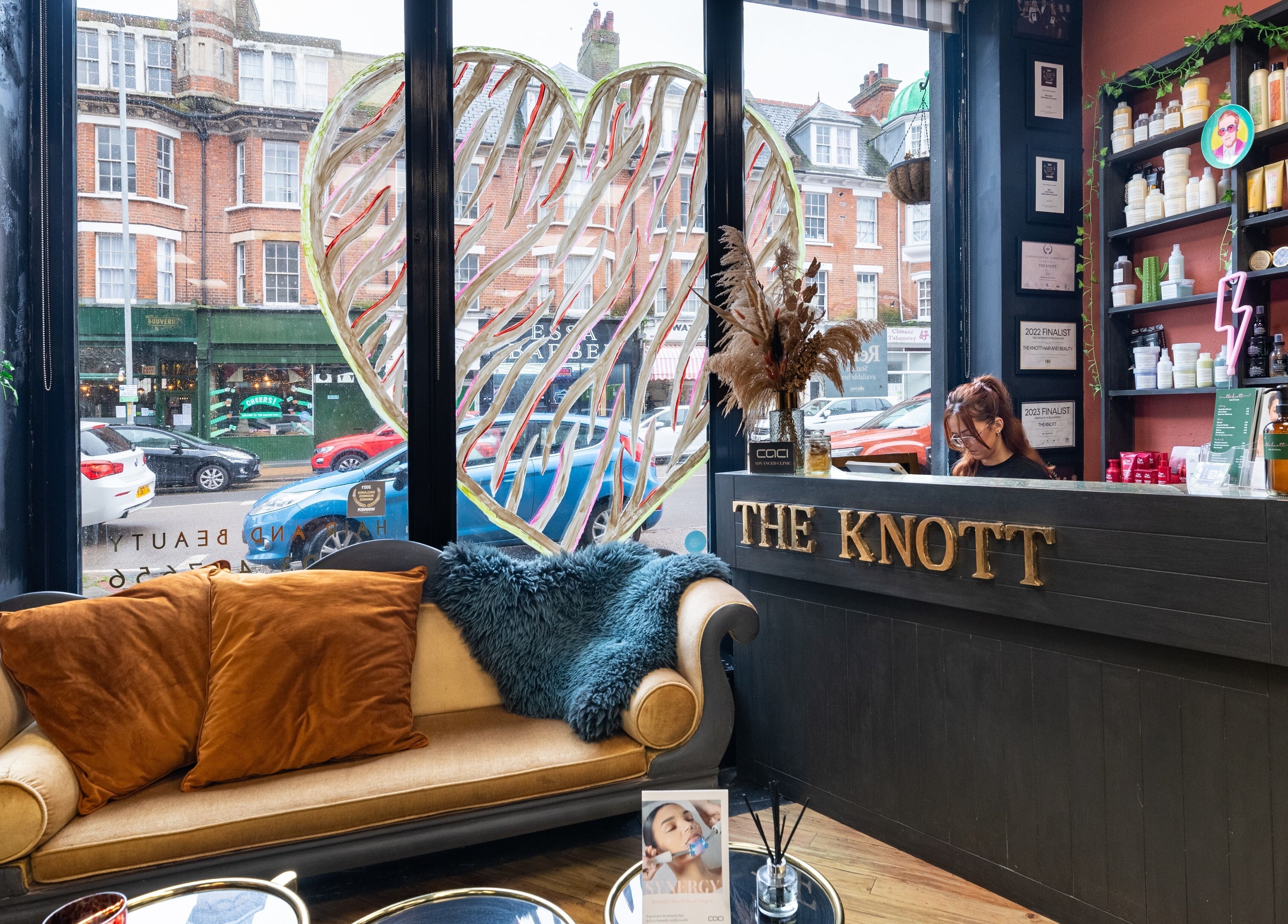 Chic interior of The Knott, a beauty and wellness venue in Folkestone, England, GB, showcasing cozy seating and products.