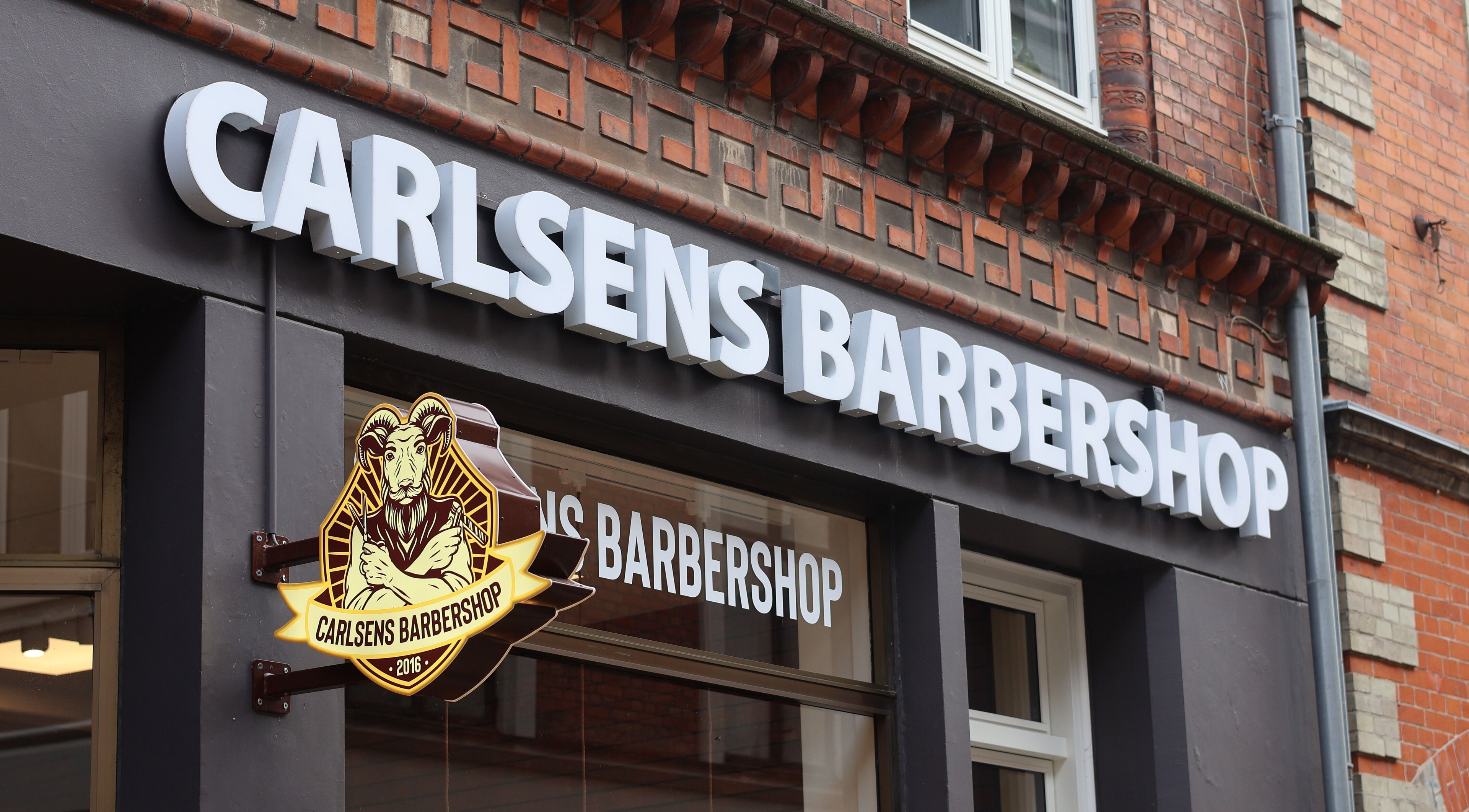 Carlsens Barbershop facade sign in Svendborg, DK. Classic barber styling on Kattesundet street.