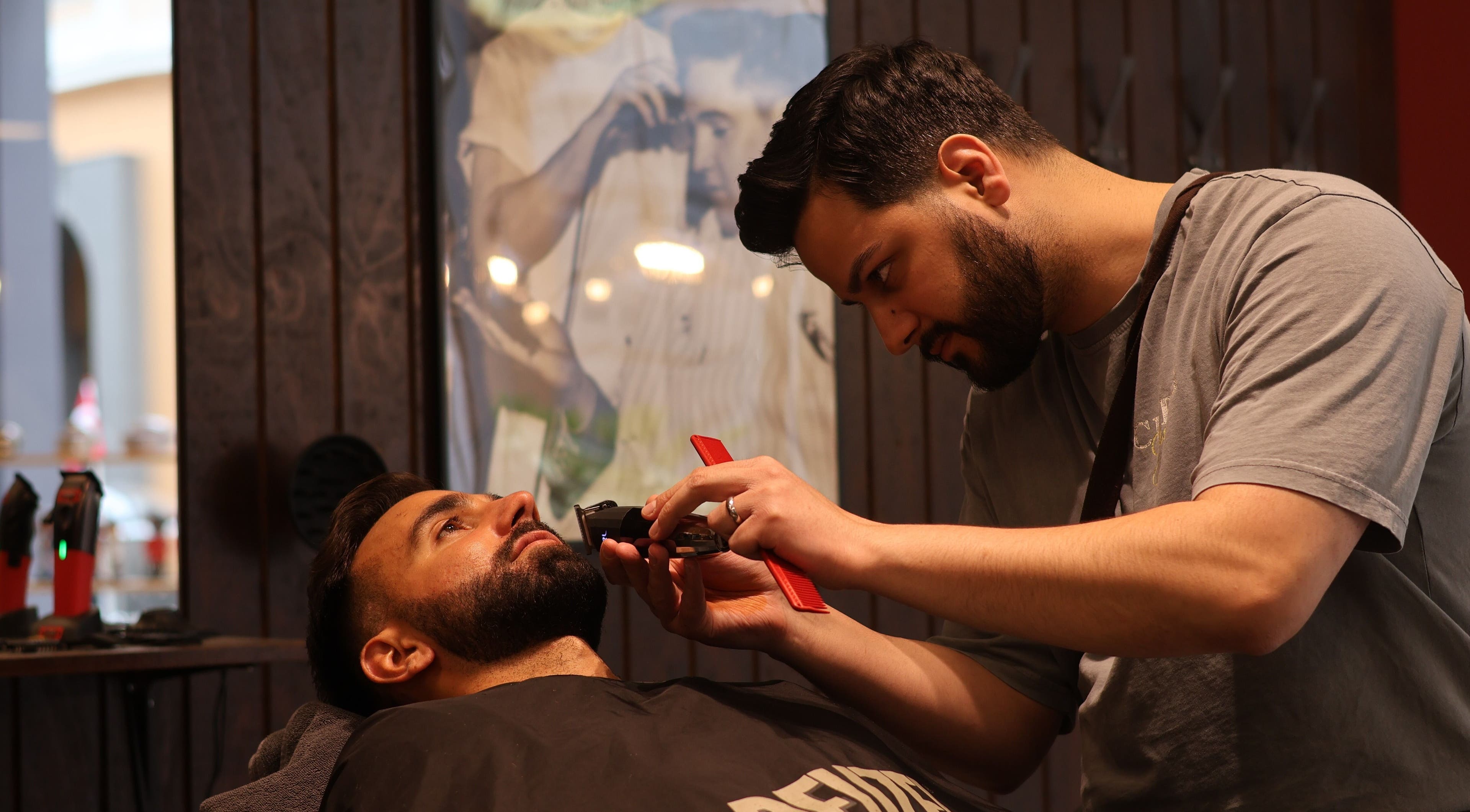 Barber at Carlsens Barbershop in Svendborg, DK grooming a client's beard with precision tools.