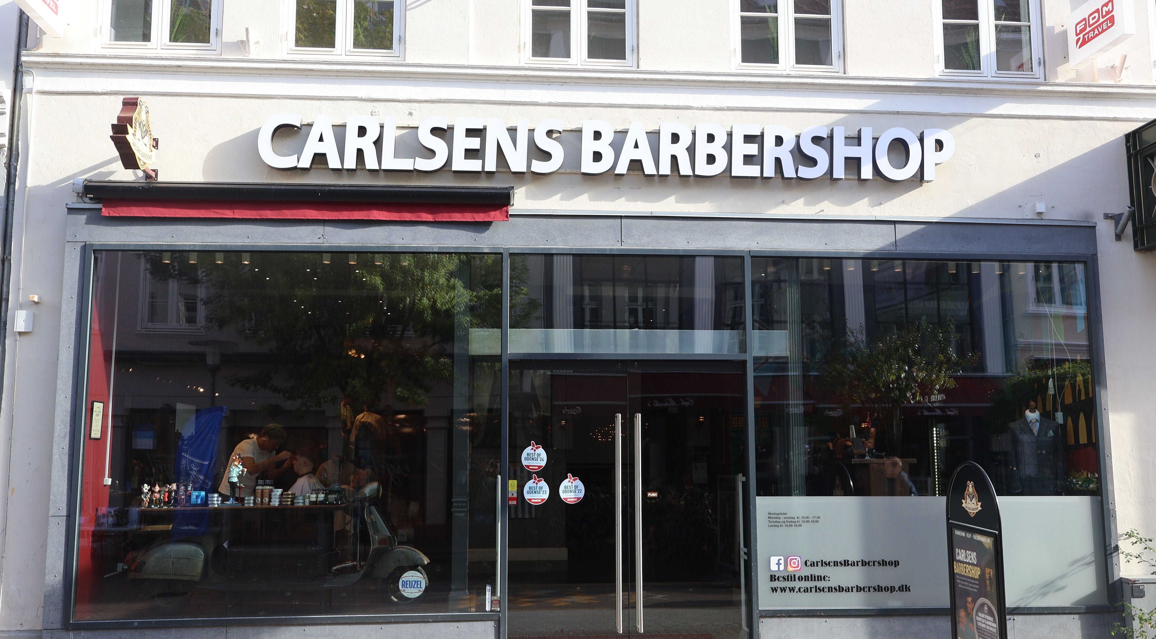 Exterior view of Carlsens Barbershop on Kongensgade, Odense, DK, showcasing the stylish entrance.