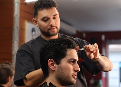 Expert barber at Carlsens Barbershop (Aarhus • Frederiksgade) skillfully cutting hair, Aarhus, DK.