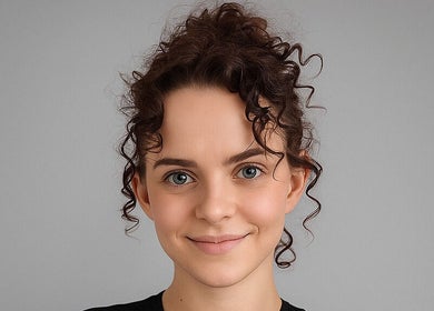 A smiling client with styled curly hair at Spectrum Cuts, Arlesey, England, GB.