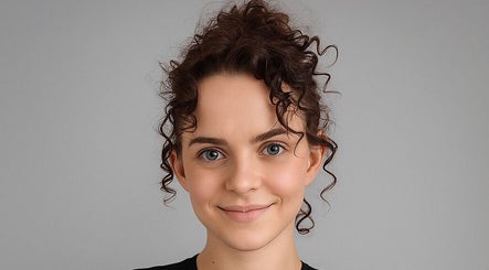 A smiling client with styled curly hair at Spectrum Cuts, Arlesey, England, GB.