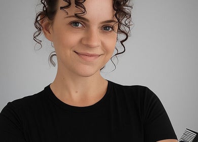 Portrait of a hairstylist at Spectrum Cuts, Arlesey, England, GB, holding a comb with a friendly smile.