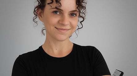 Portrait of a hairstylist at Spectrum Cuts, Arlesey, England, GB, holding a comb with a friendly smile.