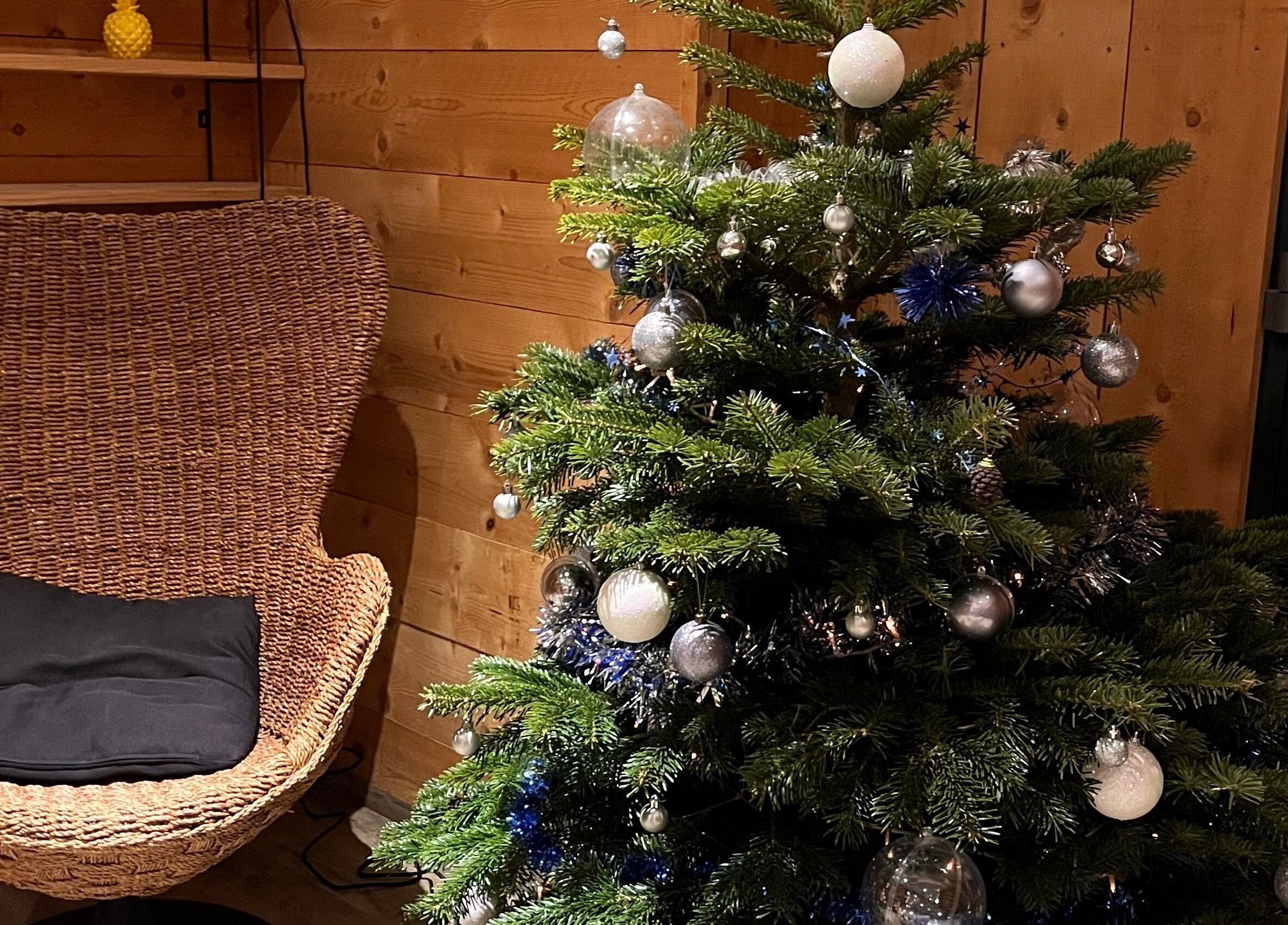 Sapin décoré à Marion PRĀNA, Crespières, Île-de-France, FR avec fauteuil en osier.