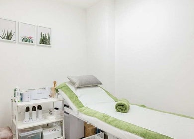 Treatment room at YM London, London, England, GB showcasing a cozy bed with green accents.